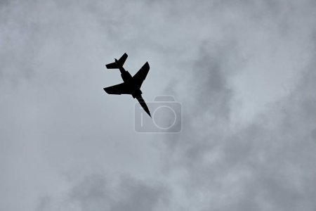 Téléchargez les photos : Avion de chasse à réaction silhouette contre ciel nuageux sombre - en image libre de droit