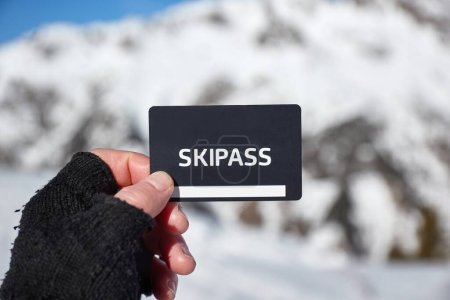 Ski pass held in hand by skier in a snowy mountain landscape