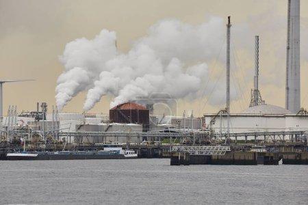 Industrial dock oil terminal and power plants emitting smoke and steam, crude storage silos