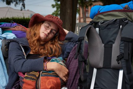 Reisenden in bunten Kleidern schlafend auf einer Bank am Bahnhof, junge Frau, die durch die Welt reist