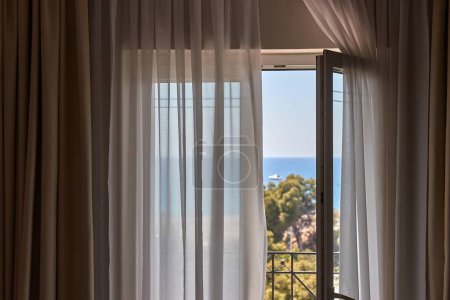 Téléchargez les photos : Chambre vue mer avec balcon porte ouverte en été bord de mer ensoleillé - en image libre de droit