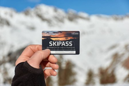 Photo for Alpe dHuez, France - January 26, 2022: Ski pass held in hand by skier in a snowy mountain landscape Oz Vaujany, part of Alpe dHuez ski resort - Royalty Free Image