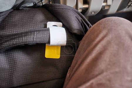 Téléchargez les photos : Sac cabine sur un vol avec étiquette pour bagage à main garantie ajustement entre les jambes et sous le siège à l'avant - en image libre de droit