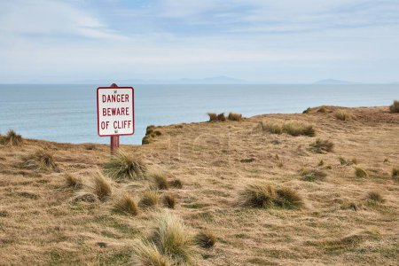 Photo for Warning sign beware of cliff on a coastal rock formation, view on the sea - Royalty Free Image