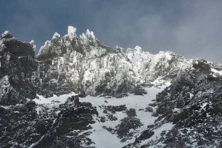 Photo for High mountain range in winter, rocky cliffs with ice in snow storm - Royalty Free Image