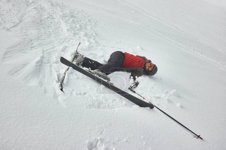 Photo for Skier falling in a turn, lying on the ground in deep snow - Royalty Free Image