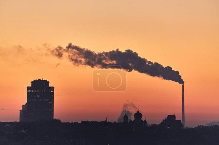 Photo for Smoking power plant chimney over a town - Royalty Free Image