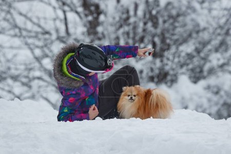 Skier stopping to play with a cute dog in the snow.