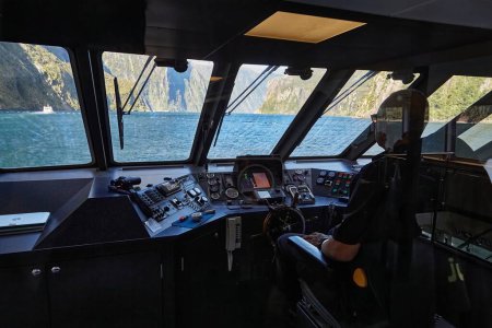 Photo for Milford Sound, New Zealand - March 17, 2016: Landscape at Milford Sound, New Zealand. Going on a touristic boat ride, view of the control room of the ship, navigator looking through the windscreen - Royalty Free Image
