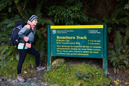 Photo for Fiordland, New Zealand - March 17, 2016: Hiker girl standing in front of the information board of Routeburn Track trailhead, start of a great walk tramping hiking trail in New Zealand South Island - Royalty Free Image
