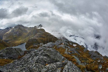 High mountain landscape along the Routeburn Track, Great Walk hiking trail in New Zealand South Island, foggy weather, cliffs and lake
