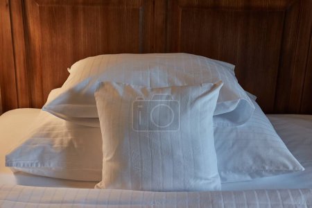 Bed detail in a hotel room, pillows in cozy moody light