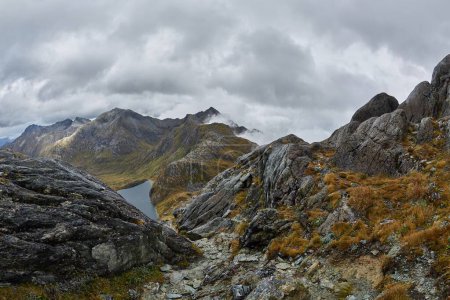 High mountain landscape on the Routeburn Track, Great Walk hiking trail in New Zealand South Island, foggy weather, cliffs, lake and clouds