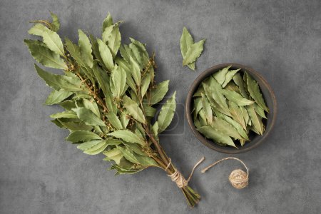 Photo for Bowl of dried laurel leaves and bunch of dry green bay leaves, top view, flat lay. - Royalty Free Image