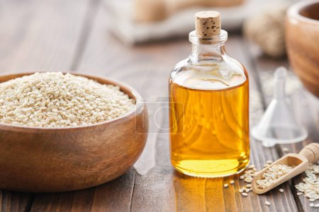 Photo for Sesame seeds in bowl and bottle of sesame oil on wooden table. - Royalty Free Image