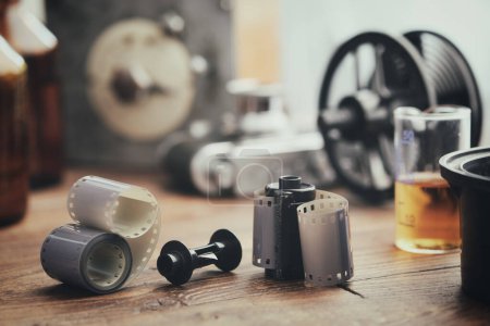 Téléchargez les photos : Rouleaux de film photo anciens, cassette et équipement photographique en arrière-plan - réservoir en développement avec ses bobines de film, appareil photo rétro, minuterie et réactifs chimiques. - en image libre de droit