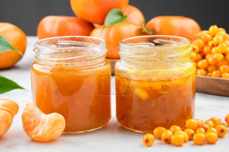 Photo for Jars of healthy sea buckthorn and tangerine jam. Plate of sea buckthorn berries and mandarin oranges fruits on background. - Royalty Free Image