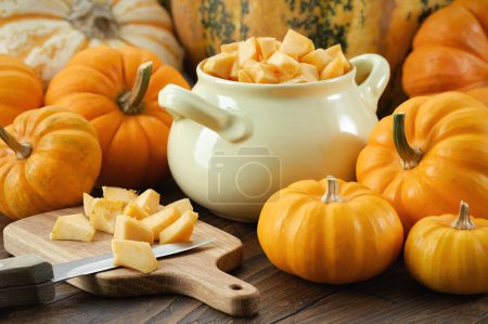 Photo for Chopped pumpkin pulp on a cutting board. Saucepan filled with chopped pumpkin prepared for cooking - Royalty Free Image