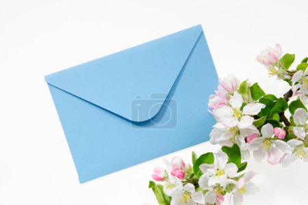 Foto de Sobre azul con tarjeta de invitación de boda o carta de cumpleaños decorada con rama de manzano en flor. Acostado. Vista superior. - Imagen libre de derechos