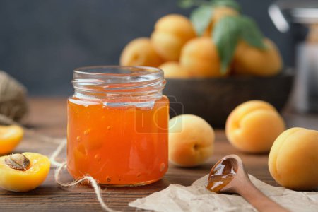 Téléchargez les photos : Pot de confiture d'abricot maison et fruits mûrs d'abricot sur la table de cuisine. - en image libre de droit