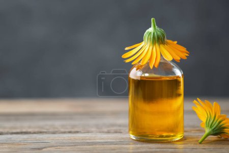 Téléchargez les photos : Bouteille d'huile essentielle de calendula ou infusion et fleurs de souci. Médecine alternative à base de plantes. - en image libre de droit