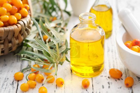 Photo for Bottles of sea buckthorn essential oil, mortar and basket of sandthorn berries. - Royalty Free Image