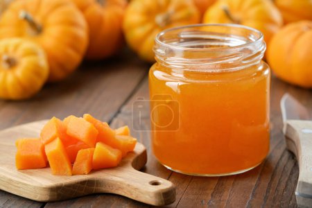 Photo for Jar of healthy pumpkin jam. Chopped pumpkin pulp on a cutting board. Pumpkins in the background. - Royalty Free Image