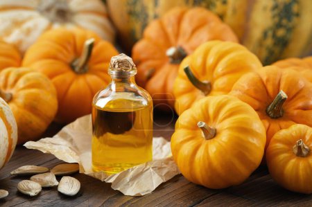 Photo for Healthy pumpkin seeds oil bottle, pumpkins on wooden kitchen table. - Royalty Free Image