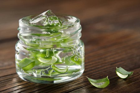 Photo for Glass jar of aloe vera gel, slice of aloe leaves on a wooden board. Natural cosmetic and medicinal remedy. - Royalty Free Image