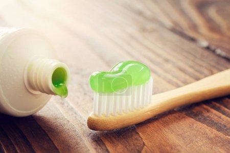 Téléchargez les photos : Brosse à dents en bois écologique en bambou avec dentifrice et tube de dentifrice à base de plantes gros plan. - en image libre de droit