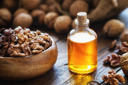Foto de Cuenco de madera de nueces y botella de aceite esencial de nuez en la mesa de la cocina. - Imagen libre de derechos