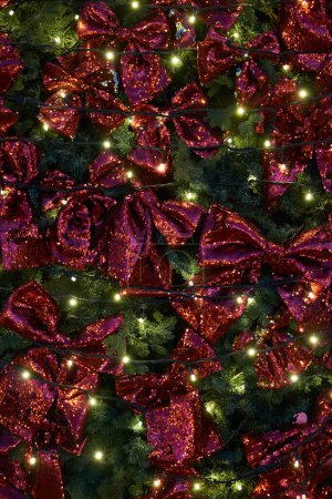 Foto de Fondo de Navidad - ramas de abeto decoradas con arcos rojos y luces iluminadas. - Imagen libre de derechos