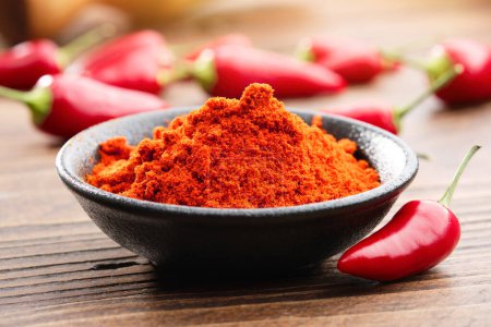 Photo for Bowl of red chili pepper ground to powder and whole red hot pepper pods on background. - Royalty Free Image