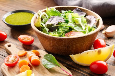 Téléchargez les photos : Salade de légumes dans un bol et ingrédients sur une table en bois. - en image libre de droit