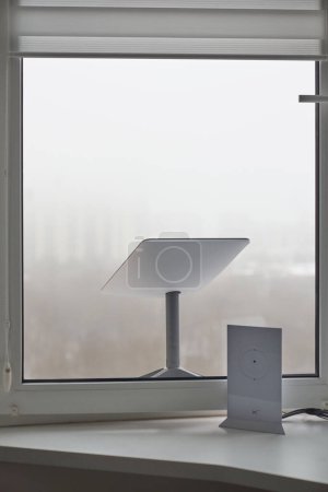 Photo for KYIV, UKRAINE - JANUARY 24, 2023: Starlink antenna and wi-fi router on windowsill in home interior. - Royalty Free Image