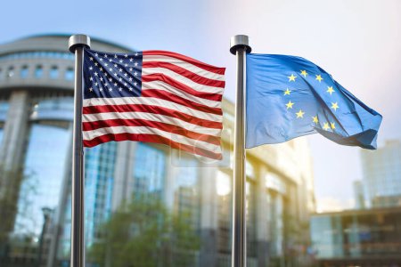 Téléchargez les photos : Les drapeaux des États-Unis et de l'Union européenne flottent sur fond de bâtiment du Parlement européen à Bruxelles. Symbole de coopération entre les pays - en image libre de droit
