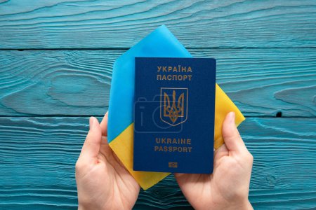 Foto de Pasaporte internacional de Ucrania en manos femeninas en el contexto de la bandera nacional. guerra contra Ucrania - Imagen libre de derechos