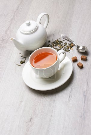 Foto de Taza de té y tetera, cuchara, azúcar, sobre un fondo de madera clara - Imagen libre de derechos