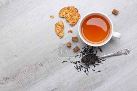 Téléchargez les photos : Tasse de thé et biscuits, cuillère, sucre, sur un fond de bois clair - en image libre de droit