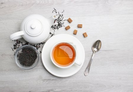 Photo for Cup of Tea and teapot, spoon, sugar, on a light wooden background - Royalty Free Image