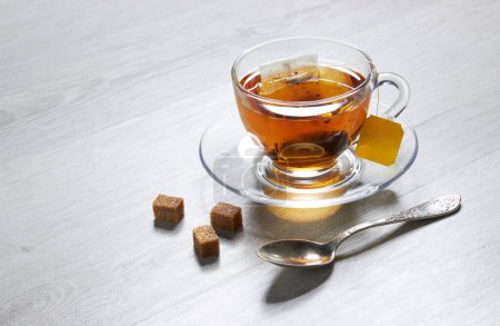 Photo for Cup of Tea and teabag, spoon, sugar, on a light wooden background - Royalty Free Image