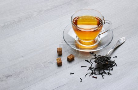Téléchargez les photos : Tasse de thé et cuillère, sucre, sur un fond de bois clair - en image libre de droit