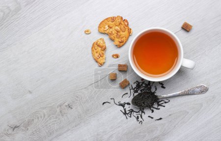 Foto de Taza de té y galletas, cuchara, azúcar, sobre un fondo de madera clara - Imagen libre de derechos