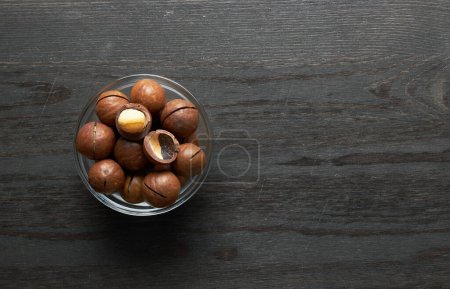 Photo for Macadamia nuts in bowl on a wooden background - Royalty Free Image