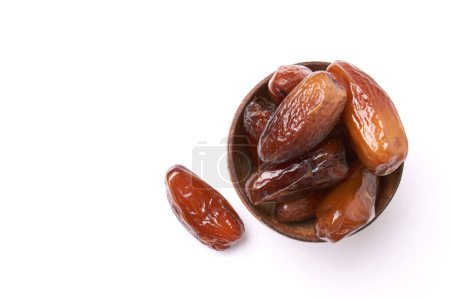 Dried dates fruits in wooden bowl isolated on white background