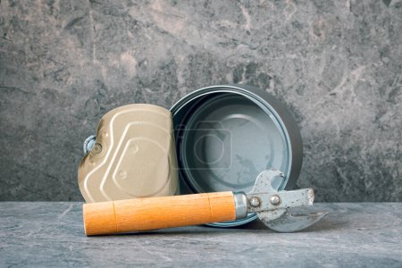 Can opener and empty tin can on the stone background. Diet or starvation concept.