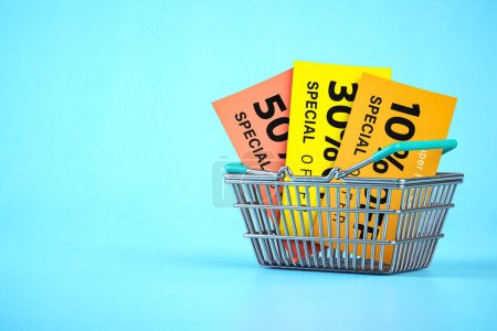 Foto de Shopping basket with discount flyers and vouchers on blue background.. Sales promocional poster. 3d illustration - Imagen libre de derechos