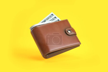 Foto de Purse or wallet with money dollar bills on yellow background. 3d illustration - Imagen libre de derechos
