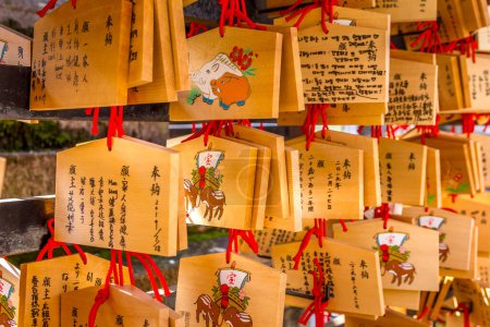 Téléchargez les photos : Kyoto, Japon - 9 janvier 2023 : Bons vœux écrits sur des plaques de prière en bois (Ema). Ils sont laissés accrochés au sanctuaire, où les kami (esprits ou dieux) sont censés les recevoir. - en image libre de droit