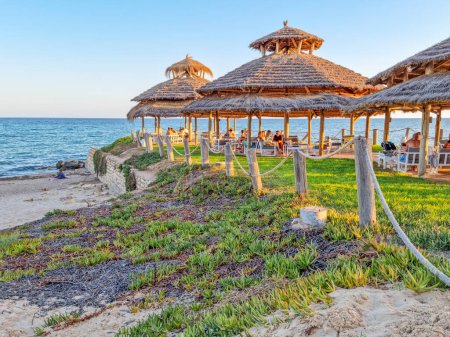 Téléchargez les photos : Hammamet, Tunisie - 24 août 2022 : Les gens profitent du coucher de soleil sur la mer. La ville est une destination populaire pour la natation et les sports nautiques et est l'une des principales destinations touristiques en Tunisie. - en image libre de droit